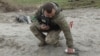 Seorang tentara pencari ranjau tampak mengambil serpihan bom tandan yang gagal meledak di area dekat desa Motyzhyn, di Kyiv, Ukraina, pada 10 April 2022. (Foto: Reuters/Mykola Tymchenko)