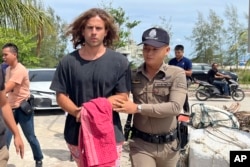 Seorang petugas polisi Thailand mengawal Daniel Sancho Bronchalo dari Spanyol atas dugaan pembunuhan dan pemotongan seorang ahli bedah Kolombia dari pulau Koh Phagnan ke pengadilan Pulau Koh Samui, Thailand selatan, Senin, 7 Agustus 2023. (AP Photo/Somkeat Ruksaman)