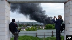 Foreign journalists report from an observation point while smoke rises after a Russian attack in Kharkiv, Ukraine, May 17, 2024.
