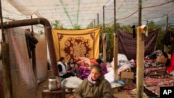 People sit inside a greenhouse, where they shelter with relatives following the earthquake in Samandag, southern Turkey, Feb. 16, 2023.