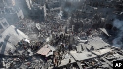 FILE - Palestinians inspect the rubble of destroyed buildings following Israeli airstrikes on town of Khan Younis, southern Gaza Strip on Oct. 26, 2023.