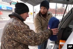 Will Compton, right, gives Luke Hall a blanket, Jan. 18, 2024, in Nashville, Tennessee.