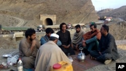 Drivers drink green tea close to their stranded trucks loaded with supplies for Afghanistan on Feb. 21, 2023, as they wait for the opening of the Torkham crossing point, which was closed by Afghan Taliban rulers.