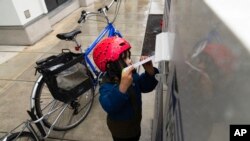 Ramona McCune, 4, slips a vote-by-mail ballot into a dropbox during primary voting in Portland, Oregon, May 21, 2024. Ramona was helping a parent drop off ballots for friends.
