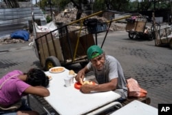 People eat a free lunch at the Casa Comunitaria del Fondo soup kitchen in Buenos Aires, Argentina, Dec. 14, 2023. Argentine President Javier Milei has taken office at a time when the nation is being ravaged by inflation.