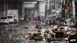 Residents look at their belongings in the aftermath of Typhoon Gaemi in Manila on July 25, 2024.