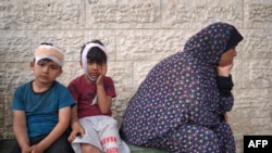 ইসরায়েলি বোমা হামলায় নিহত স্বজনদের মৃতদেহ শনাক্ত করতে গাজার দেইর আল-বালাহ'র আল-আকসা শহীদ হাসপাতালের আঙিনায় আহত ফিলিস্তিনি ছেলেরা তাদের পরিবার নিয়ে অপেক্ষা করছে। (১১ মে, ২০২৪) 