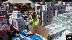 FILE - A volunteer works at a food and supply distribution center set up in the parking lot of a shopping mall in Lahaina, Hawaii, Aug. 16, 2023, after wildfire devastated parts of the Hawaiian island of Maui.