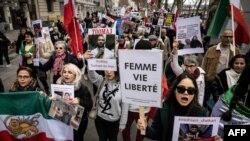 FILE - Para pengunjuk rasa memegang potret rapper Iran yang dipenjara, Toomaj Salehi (tengah) dan Mohsen Shekari (Bawah-kanan), seorang pengunjuk rasa yang dieksekusi di Iran pada bulan Desember 2022, dalam unjuk rasa di Lyon, 8 Januari 2023. (JEAN-PHILIPPE KSIAZEK / AFP)