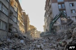 Sebuah ekskavator membersihkan puing-puing di tengah bangunan yang runtuh di Hatay pada 15 Februari 2023, sembilan hari setelah gempa berkekuatan 7,8 melanda sebagian Turki dan Suriah. (Foto: AFP)