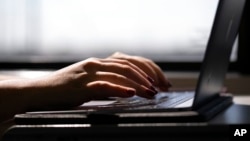FILE - This May 18, 2021, photo shows a woman typing on a laptop in New Jersey.