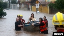 Rescue workers evacuate a family with a pet from a flooded area in the Cavalhada neighborhood in Porto Alegre, Brazil, May 23, 2024. 
