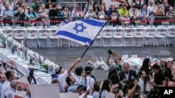 Israeli Americans and supporters hold displays of kidnapped loved ones as they rally around an installation in Times Square, featuring a Shabbat (Sabbath) table set, representing hostages still held by Hamas in the Gaza Strip, Oct. 26, 2023, in New York.