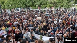 FILE - Members of rights groups carry banners during a protest, after Tunisian President Kais Saied ordered security forces to stop all illegal migration and expel all undocumented migrants, in Tunis, Tunisia, Feb. 25, 2023.