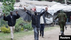 People lift their hands as they walk near a police officer during a demonstration over police killings of people protesting against Kenya's proposed finance bill 2024/2025, in Nairobi, June 27, 2024.