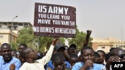 Protesters react as a man holds up a sign demanding U.S. Army soldiers leave Niger without negotiation during a demonstration in Niamey, on April 13, 2024.