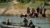 Penjaga mendorong para migran yang menunggu di gundukan pasir di tengah sungai Rio Grande untuk berbalik ketika mereka mencoba menyeberangi sungai tersebut dari Meksiko ke AS, Sabtu, 23 September 2023. (AP/Eric Gay)