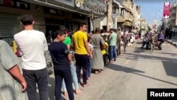 Palestinians wait to buy bread at a bakery, amid the ongoing conflict between Israel and Islamist group Hamas, in Khan Younis in the southern Gaza Strip, October 14, 2023.