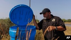 FILE - Jim Hogg County Sheriff's Investigator Ruben Garza inspects a water station for immigrants containing sealed jugs of fresh water along a fence line near a roadway in rural Jim Hogg County, Texas, July 25, 2023. 