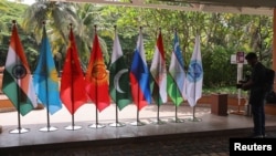 FILE - A video journalist films flags of countries participating in the Shanghai Cooperation Organization foreign ministers’ meeting, outside the venue in Goa, India, May 4, 2023.