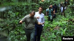 French President Emmanuel Macron walks with Gabon's Minister of Water and Forests Lee White while during his visit to the Mondah classified forest on the sidelines of the One Forest Summit in Libreville, Gabon, March 2, 2023.