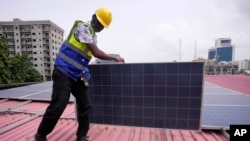 FILE - Oladapo Adekunle, an engineer with Rensource Energy, installs solar panels on a roof of a house in Lagos, Nigeria, March 21, 2024. 