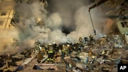 FILE - Emergency workers clear the rubble after a Russian rocket hit a building, leaving many people trapped under debris in the southeastern city of Dnipro, Ukraine, Jan. 14, 2023.