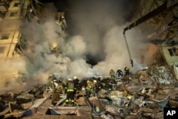 FILE - Emergency workers clear the rubble after a Russian rocket hit a building, leaving many people under debris in the southeastern city of Dnipro, Ukraine, Jan. 14, 2023.