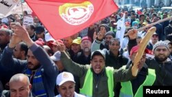 A supporter of the Tunisian General Labor Union (UGTT), carries bread as he shouts slogans during a protest against President Kais Saied's policies, accusing him of trying to stifle basic freedoms including union rights, in Sfax, Tunisia, Feb. 18, 2023. 