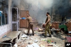 In this photo provided by district police office, a police officer puts out a fire in a burning house at a Christian neighborhood following an angry mob attack in Jaranwala near Faisalabad, Pakistan, Aug. 16, 2023.