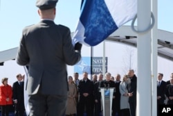Finland's President Sauli Niinisto, center, speaks as military personnel prepare to raise the flag of Finland during a the country's NATO accession ceremony at the alliance's headquarters in Brussels, April 4, 2023.