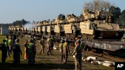 FILE - U.S. soldiers prepare to unload Bradley Infantry Fighting Vehicles from rail cars as they arrive at the Pabrade railway station near Vilnius, Lithuania, Oct. 21, 2019. 