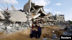 Palestinian children sit next to the site of an Israeli strike on a house amid the ongoing conflict between Israel and the Palestinian Islamist group Hamas, in Rafah in the southern Gaza Strip, April 21, 2024. 
