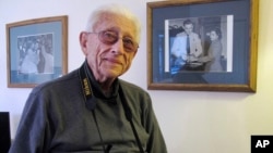 FILE - Former Associated Press photographer Gene Herrick poses between two of his most famous pictures, at his home in Rocky Mount, Virginia, Feb. 2, 2018.