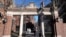 FILE - A passer-by walks through a gate to the Harvard University campus, in Cambridge, Massachusetts, Jan. 2, 2024. 