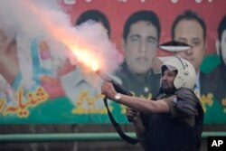 A riot police officer fires tear gas to disperse supporters of former Prime Minister Imran Khan during clashes outside Khan's residence, in Lahore, Pakistan, March 14, 2023.