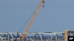 Trabajadores en una grúa trabajan en el puente derrumbado Francis Scott Key de Baltimore, el sábado 30 de marzo de 2024. 