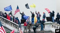 FILE — Rioters wave flags on the West Front of the U.S. Capitol in Washington on Jan. 6, 2021. The federal judge assigned to the election fraud case against former President Donald Trump stands out as one of the toughest punishers of rioters who stormed the U.S. Capitol that day.