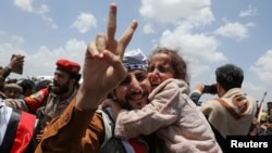 A freed prisoner gestures while holding a child after arriving at Sanaa Airport on an International Committee of the Red Cross (ICRC)-chartered plane, amid a prisoner swap between two sides in the Yemen conflict, in Sanaa, Yemen, April 14, 2023.