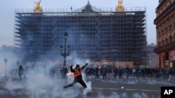 A protester kicks a tear gas canister in front of the Opera at the end of a rally in Paris, March 23, 2023.