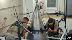 FILE - Senior Airman Jacob Deas and Airman 1st Class Jonathan Marrs secure the titanium shroud at the top of a Minuteman III intercontinental ballistic missile on Aug. 24, 2023, at the Bravo 9 silo at Malmstrom Air Force Base in Montana.