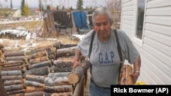 Arthur John, a retired trapper, carries firewood to his home Thursday, Sept. 23, 2021 in the Native Village of Tanacross, Alaska. COVID of robbed him of the lifestyle he so enjoyed, such as using a chainsaw to chop enough wood to heat their house through winter. 