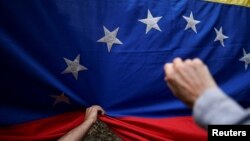 ARCHIVO - Los seguidores de la líder opositora venezolana María Corina Machado sostienen una bandera nacional durante su discurso mientras recorre el país, en San Antonio de los Altos, Estado Miranda, Venezuela, 17 de abril de 2024. 