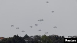 Humanitarian aid falls through the sky towards the Gaza Strip after being dropped from an aircraft, amid the ongoing conflict between Israel and the Palestinian Islamist group Hamas, as seen from Israel, April 25, 2024. 