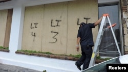 A man boards up the windows of a restaurant in Cabo San Lucas, Mexico, as Hurricane Hilary rushes toward Mexico's Baja California peninsula, on Aug. 18, 2023.