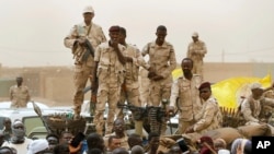FILE - Sudanese soldiers from the Rapid Support Forces unit stand on their vehicle during a military-backed rally, in Mayo district, south of Khartoum, Sudan, June 29, 2019.