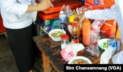 សិស្សានុសិស្ស​កំពុង​ឈរ​ដាក់​គ្រឿងទេស​ក្នុង​ស៊ុប​ដែល​ពួកគេ​បាន​ទិញ នៅ​វិទ្យាល័យ ជាស៊ីមចំរើនរដ្ឋ ក្នុង​រាជធានីភ្នំពេញ កាលពីថ្ងៃទី២២ ខែមីនា ឆ្នាំ២០២៣។ (ស៊ឹម ចាន់សំណាង/វីអូអេ)