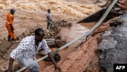 FILE - Men gather to asses the damage in the section of a road collapsing due to flash floods at the Mwingi-Garissa Road near Garissa, Kenya, on Nov. 22, 2023. 