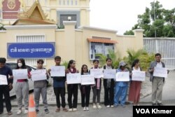 ក្រុមយុវជន និងអ្នកគាំទ្រសកម្មជនមាតាធម្មជាតិឈរលើកបដា នៅមុខសាលាដំបូងរាជធានីភ្នំពេញ នាថ្ងៃទី២៩ ខែឧសភា ឆ្នាំ២០២៤។ (ស៊ឹម ចាន់សំណាង/វីអូអេ)