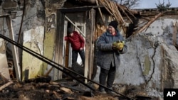 A woman holds food items found as she stands outside her house which was destroyed by a Russian drone attack in a residential neighborhood, in Zaporizhzhia, Ukraine, on March 28, 2024.